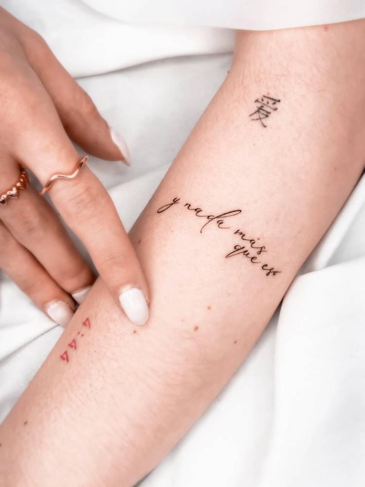 "Y nada más que eso" lettering tattoo located on the forearm.