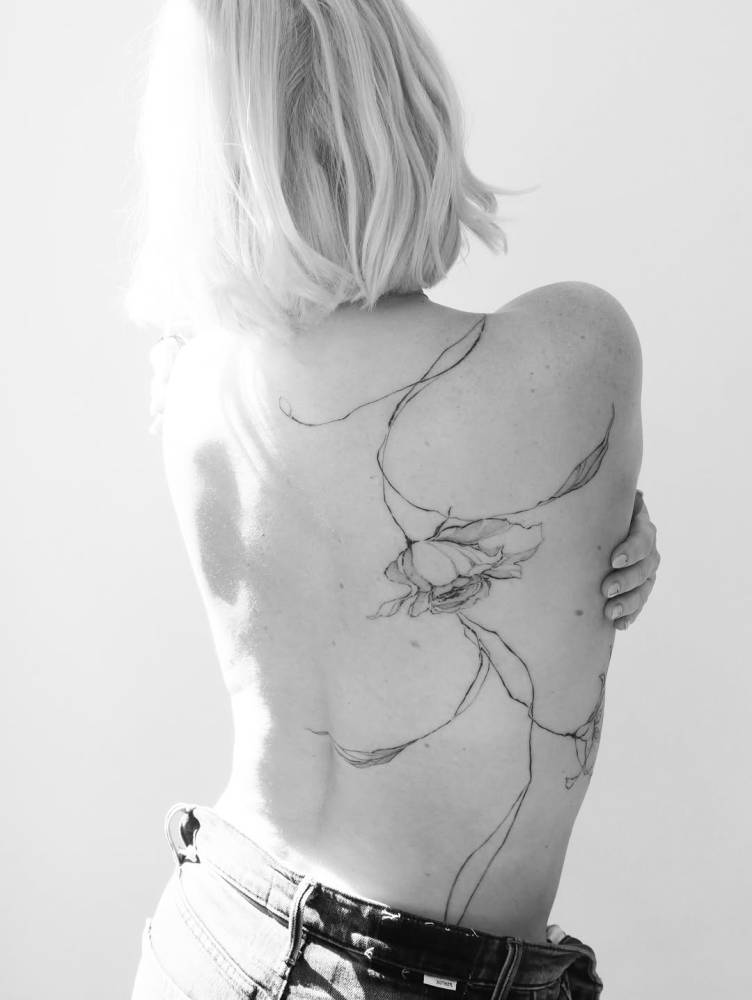 Sketch work style flower tattoo placed on the back.
