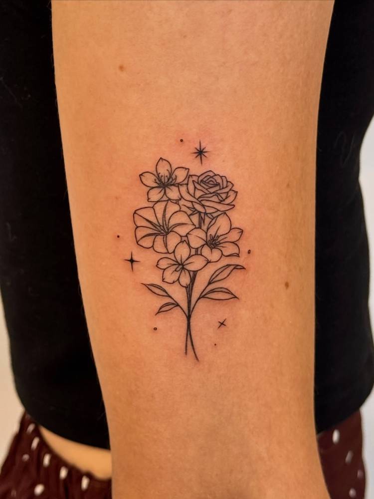 Flower bouquet tattoo in fine line style located on the upper arm.