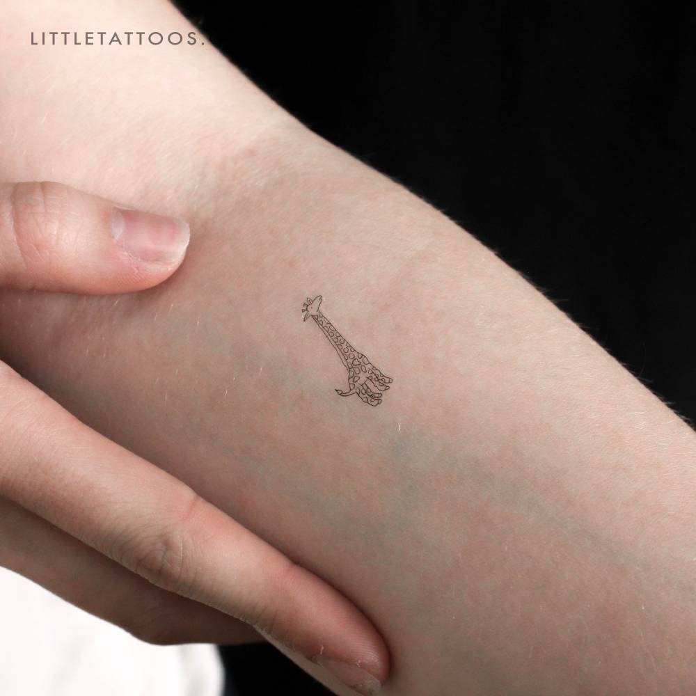 Giraffe temporary tattoo in fine line style located on the inner forearm.