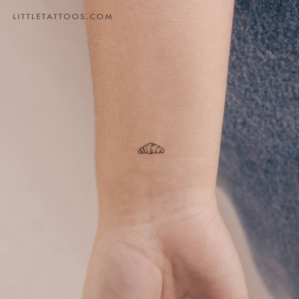 Tiny minimalistic croissant temporary tattoo located on the wrist.