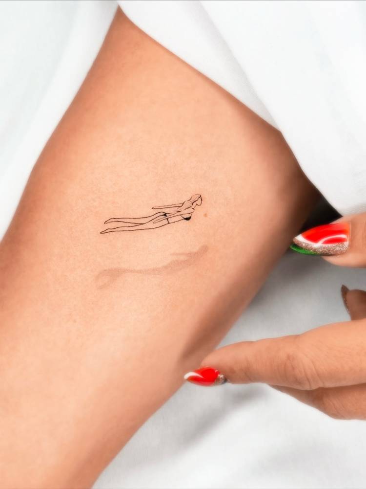 Little swimmer tattoo in fine line style located on the inner arm.