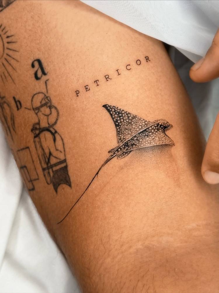 Spotted eagle ray tattoo in micro-realism located on the bicep.