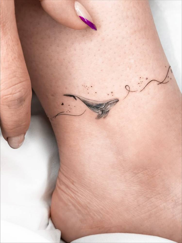 Tiny whale tattoo located on the ankle, micro-realistic style.