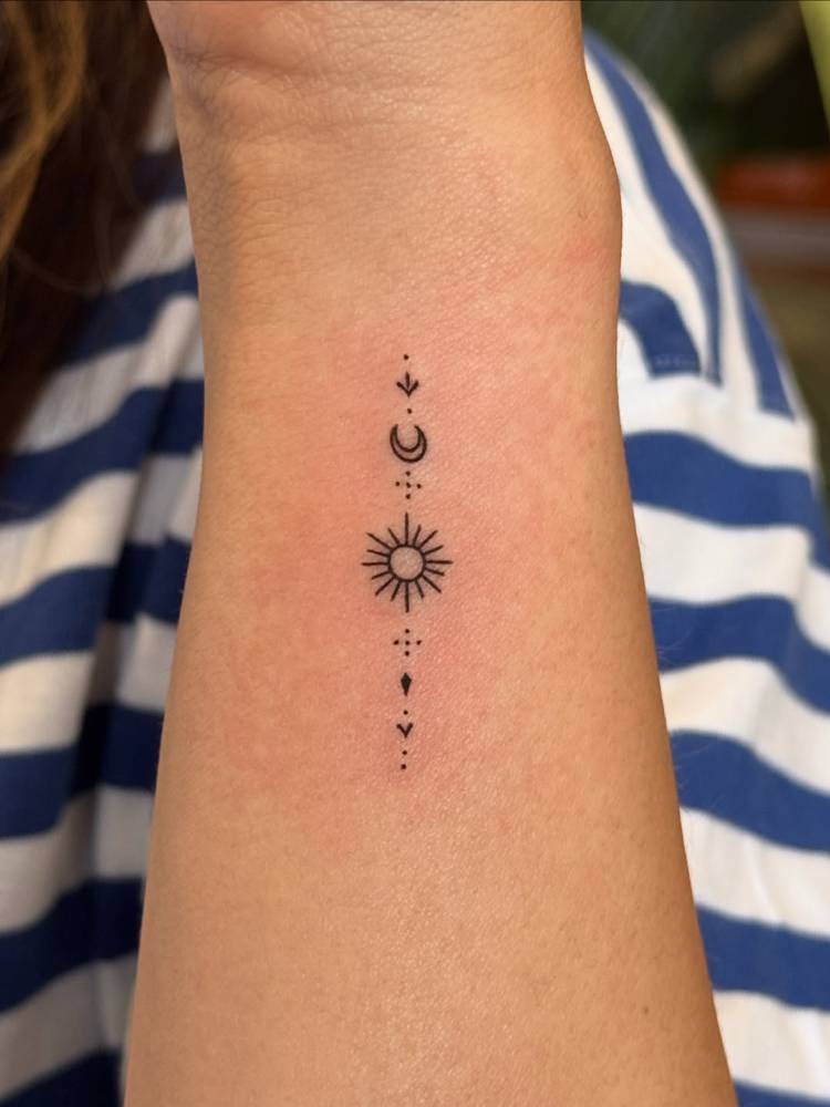 Ornamental sun and moon tattoo located on the wrist.