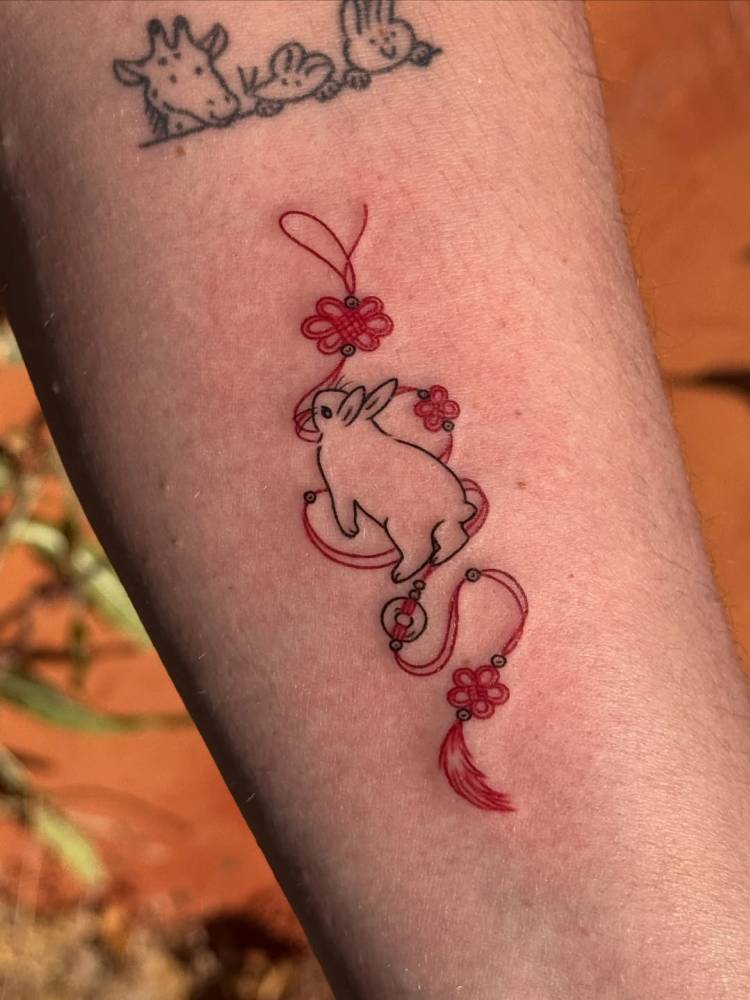 Rabbit norigae tattoo in illustrative style placed on the inner forearm.