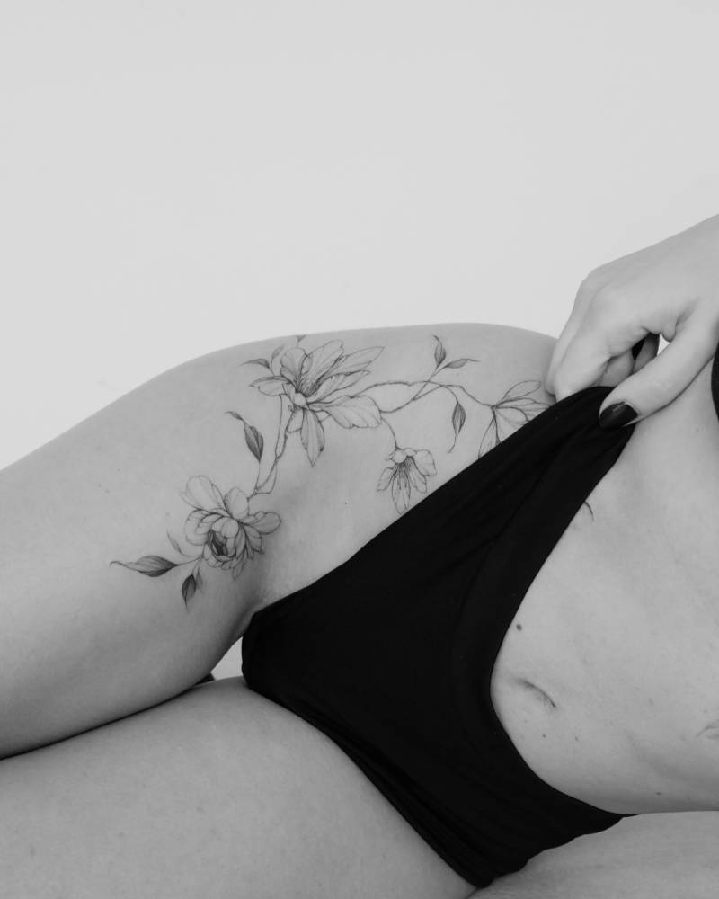 Peony and magnolia tattoo in illustrative style located on the hip.