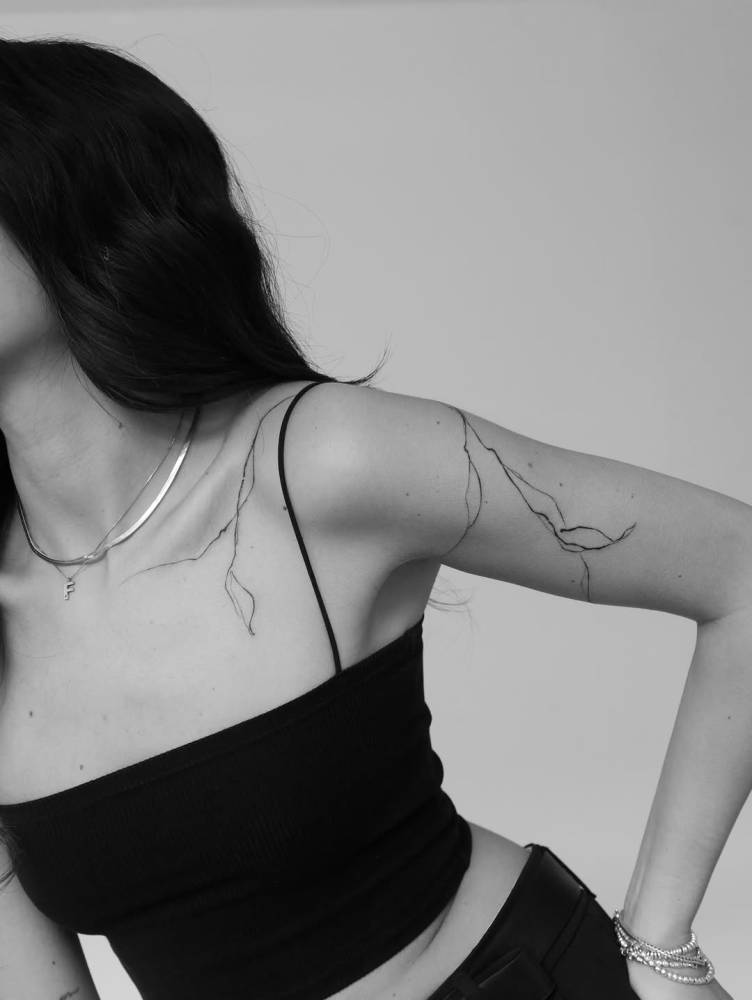 Leaves tattoo in sketch work style located on the shoulder and upper arm.