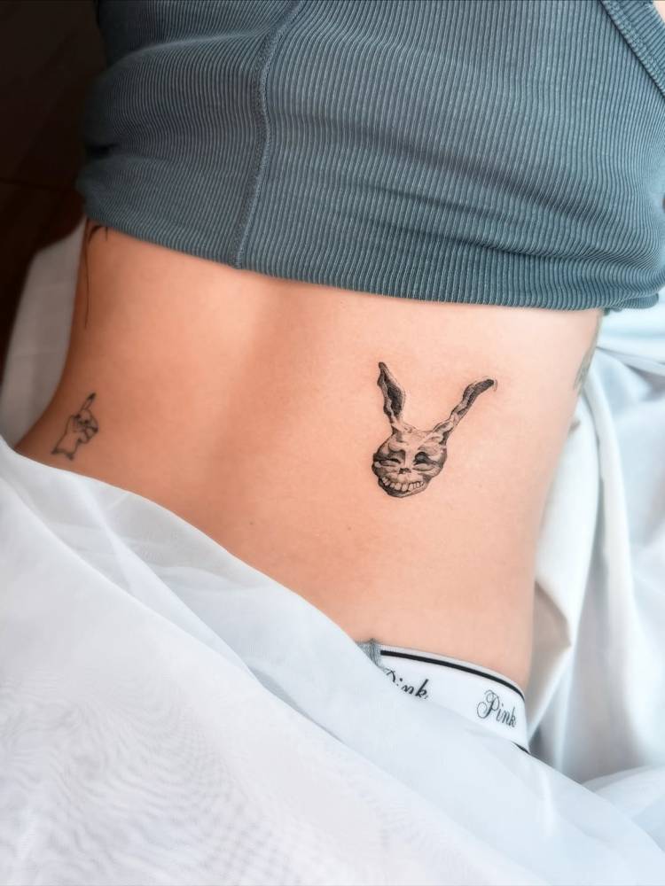 'Donnie Darko' tattoo located on the lower back, micro-realistic style.