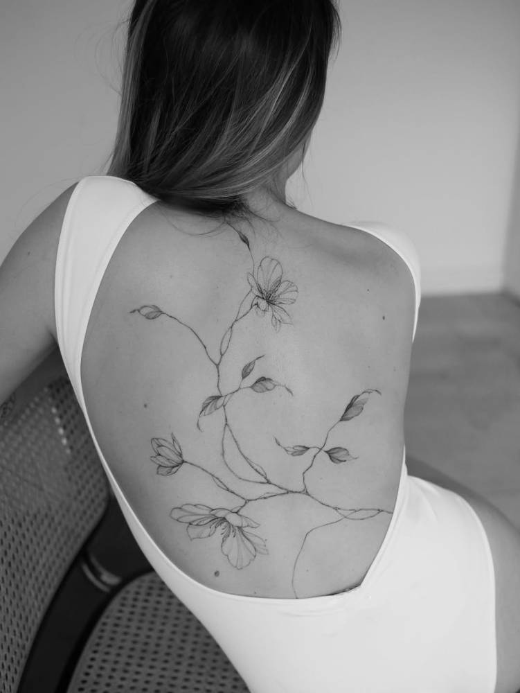 Magnolias tattoo in illustrative style located on the back.
