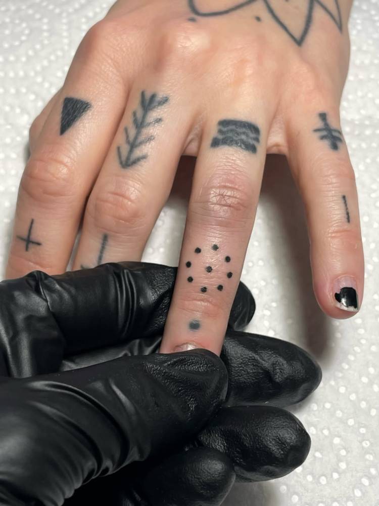 Minimalistic dots tattoo located on the finger.