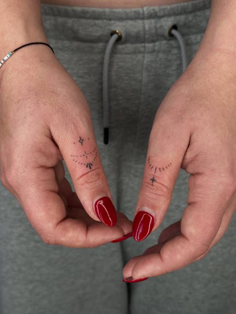 Minimalistic ornaments tattooed on the thumbs.