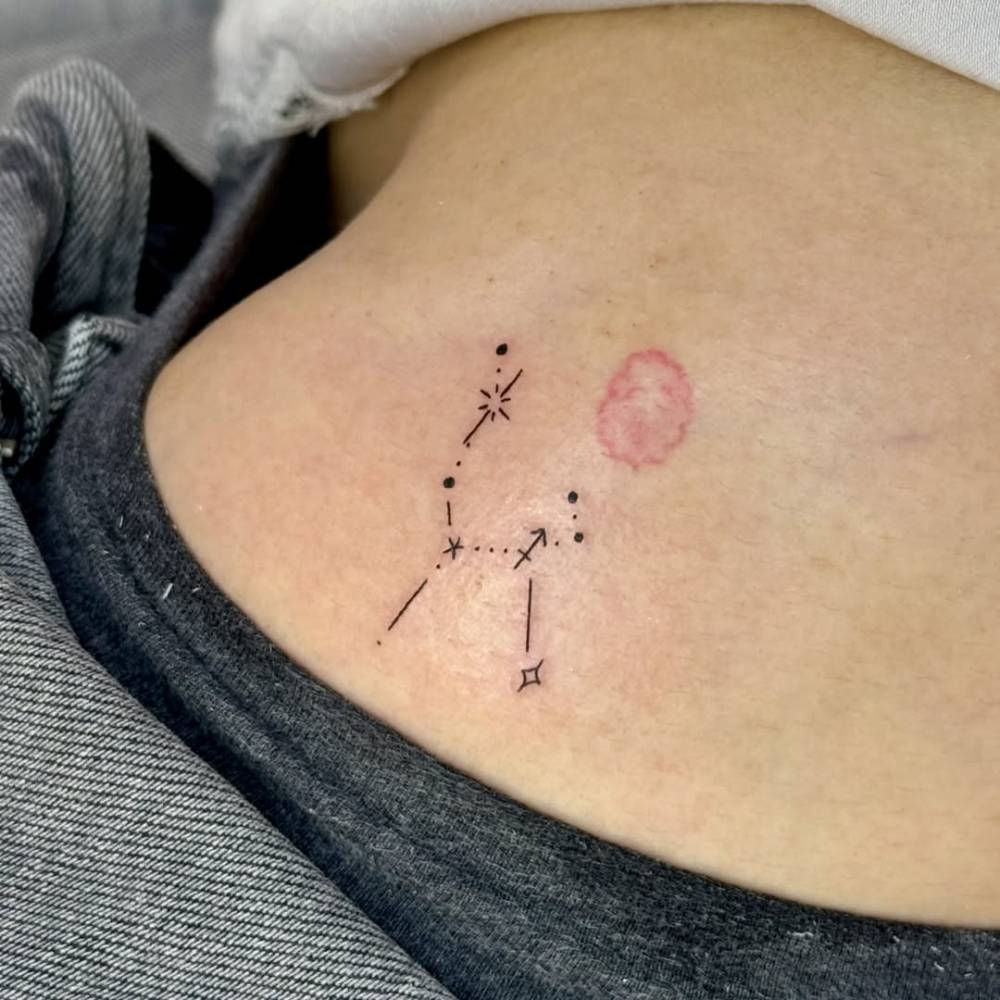 Minimalistic style Sagittarius constellation tattoo located on the hip.