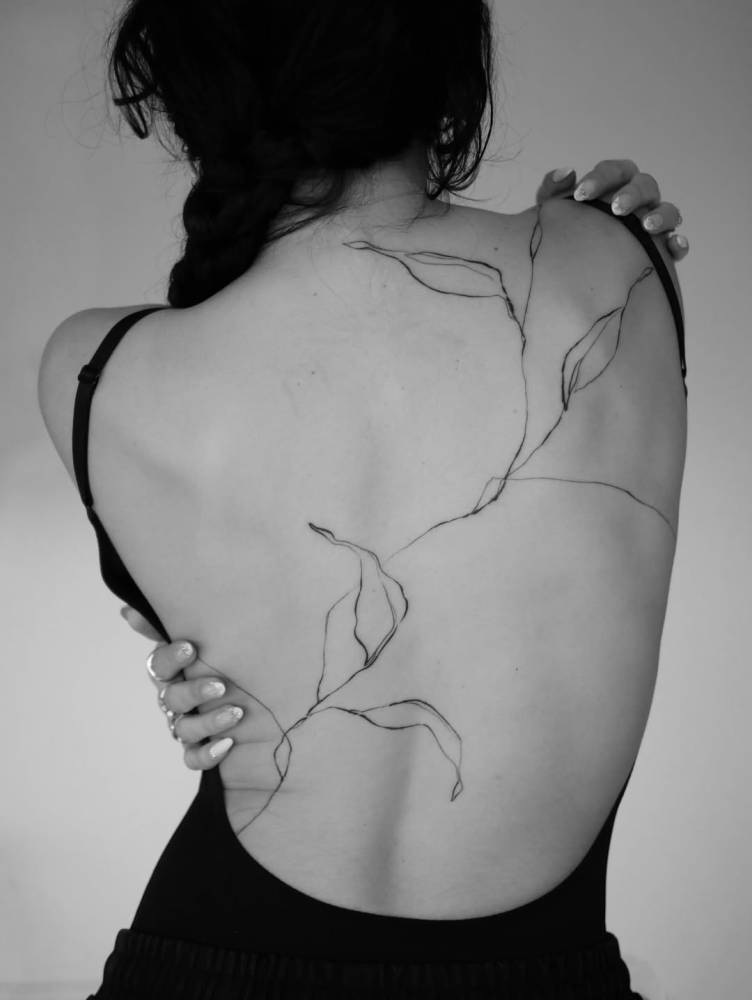 Leaves tattoo in sketch work style located on the back.