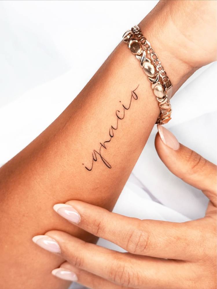 Name "Ignacio" in script font tattooed on the wrist.
