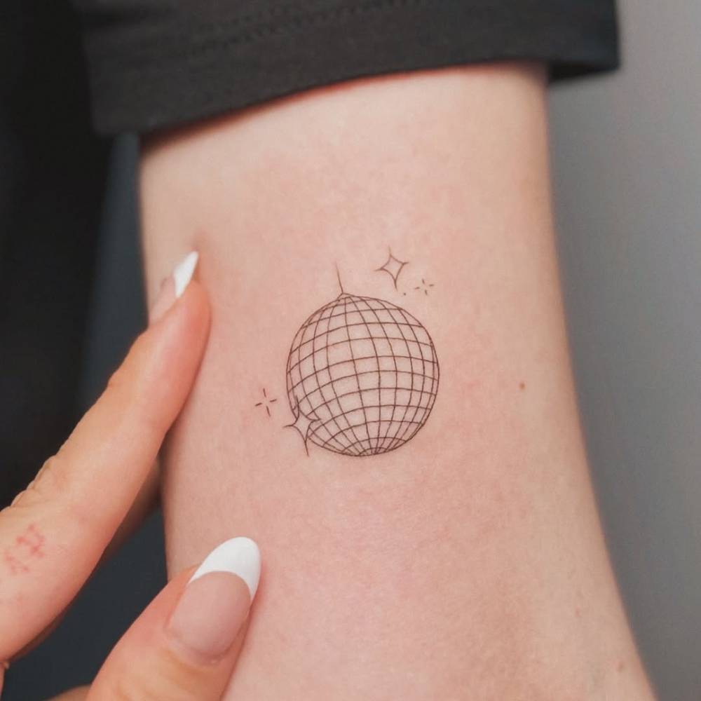Fine line style disco ball tattoo located on the bicep.