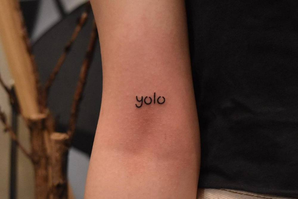 "YOLO" lettering tattoo done on the bicep.