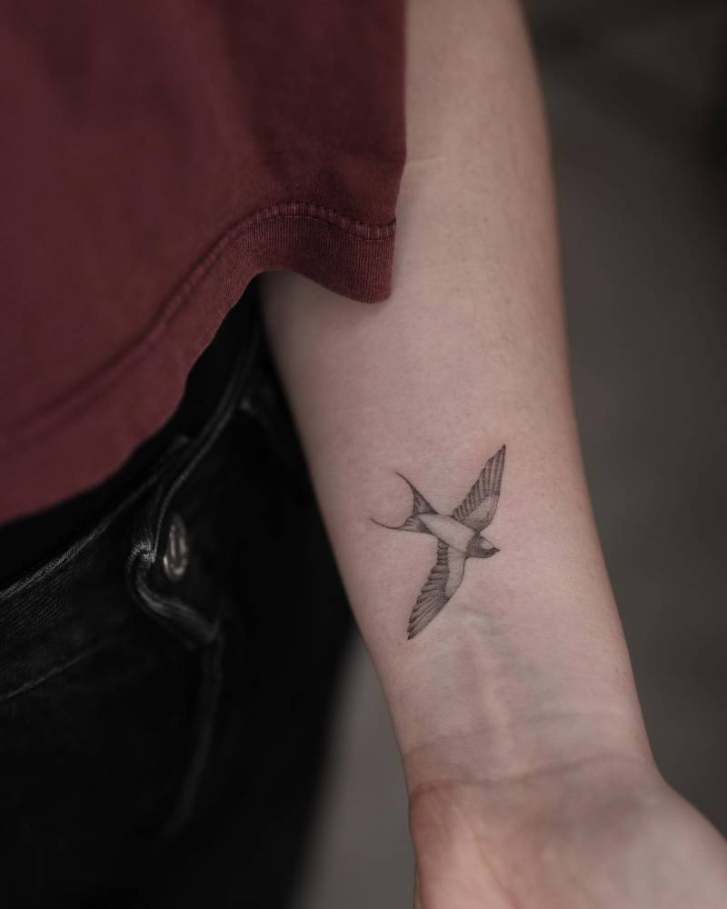 Little swallow tattoo placed on the wrist, illustrative style.