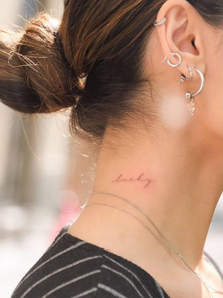 Handwritten font word "lucky" tattooed on the neck.