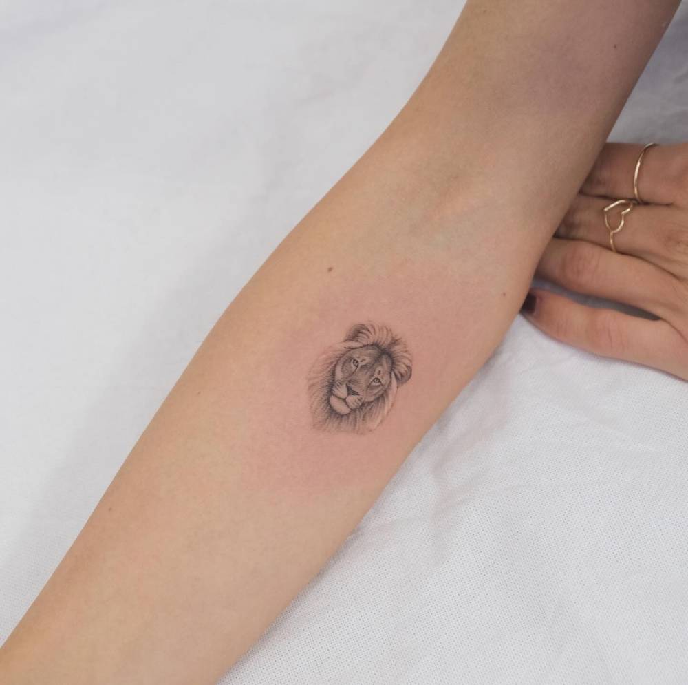 Lion portrait tattoo in micro-realistic style located on the inner forearm.