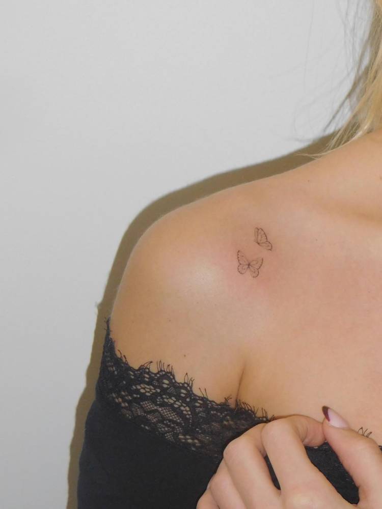 Tiny butterfly couple tattoo in fine line style located on the shoulder.