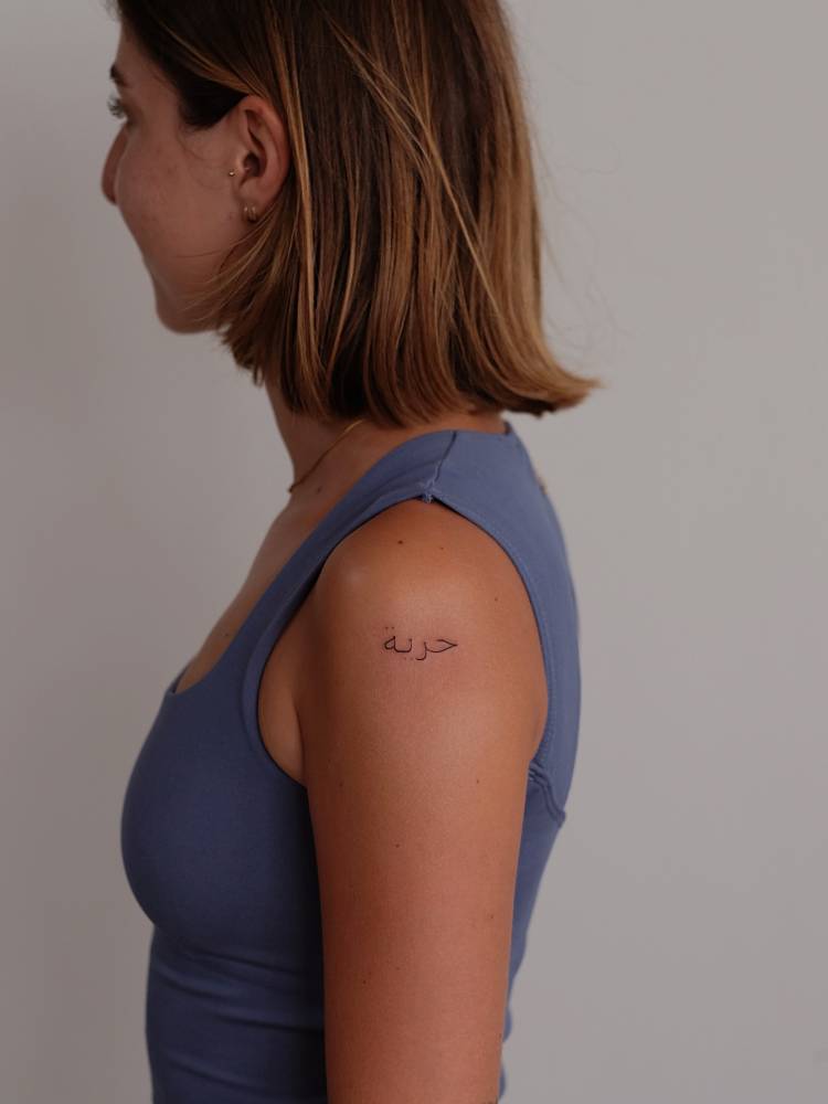 "Freedom" in Arabic tattooed on the shoulder.