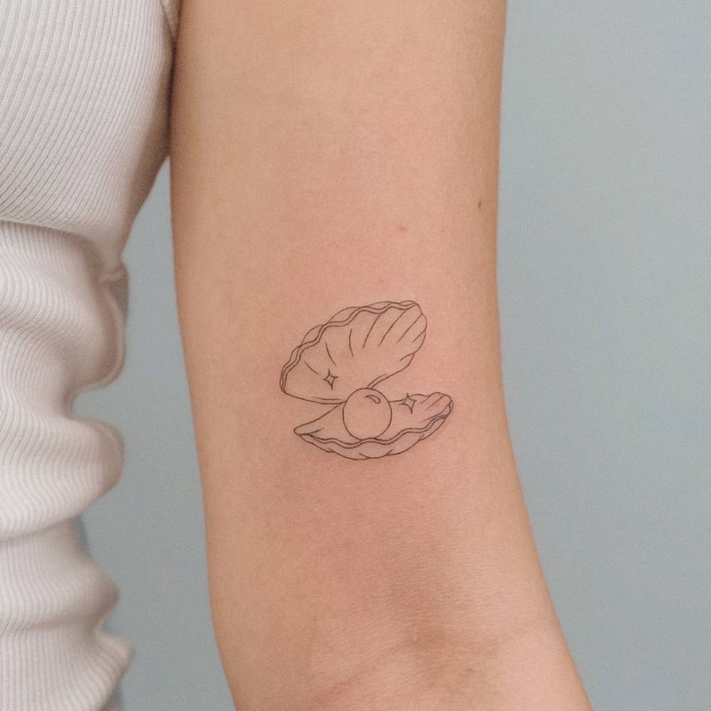 Scallop tattoo in fine line style located on the bicep.