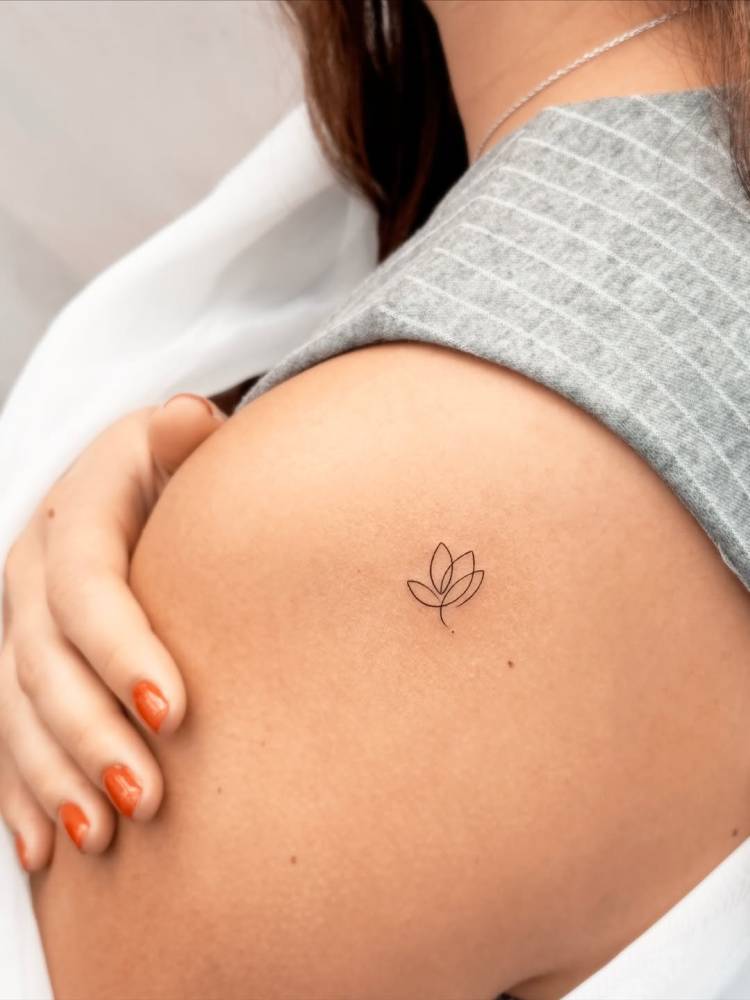 One line lotus flower tattoo located on the shoulder.