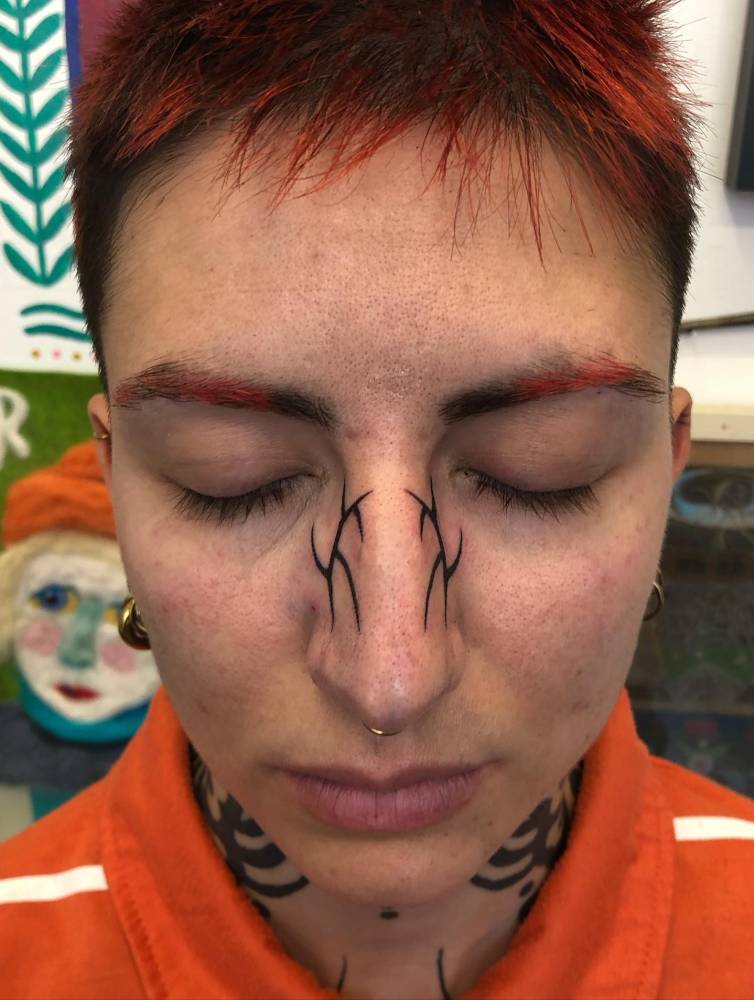 Hand poked tribal tattoo located on the face.