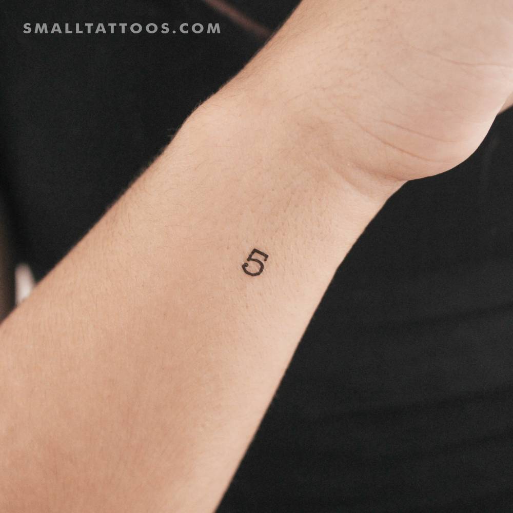Tiny number "5" temporary tattoo located on the wrist.