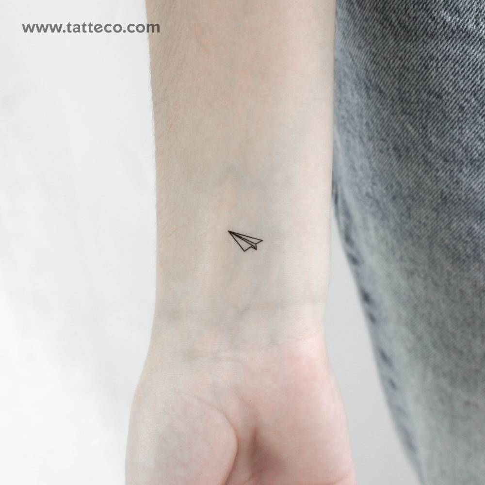 Tiny paper plane temporary tattoo in minimalistic style.