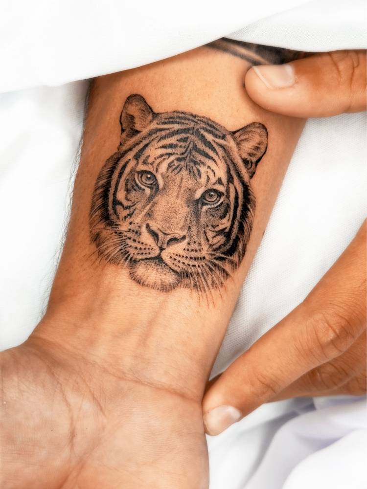 Tiger portrait tattoo located on the wrist, done in micro-realistic style.