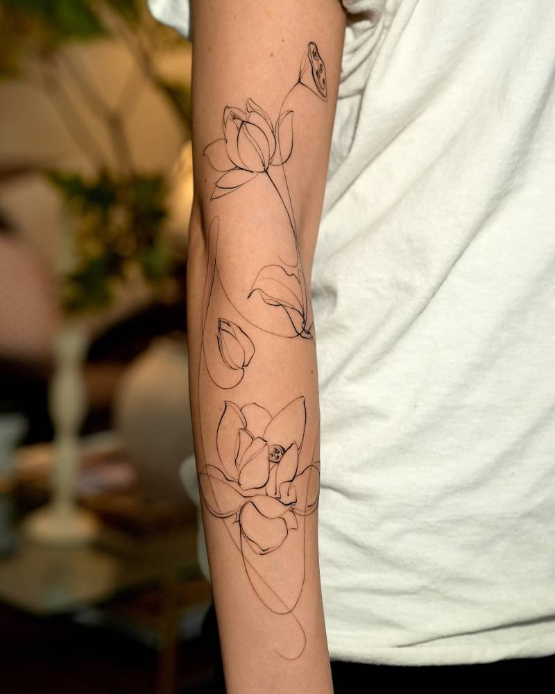 Sketch work style lily flowers tattoo located on the arm.