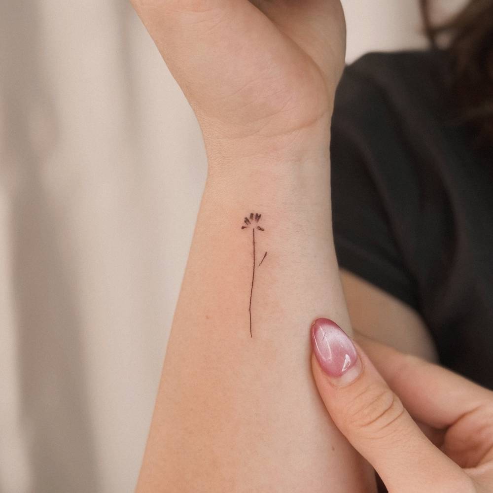 Minimalistic flower tattoo located on the wrist.