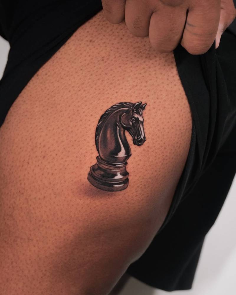 Chess knight tattoo in micro-realistic style located on the thigh.