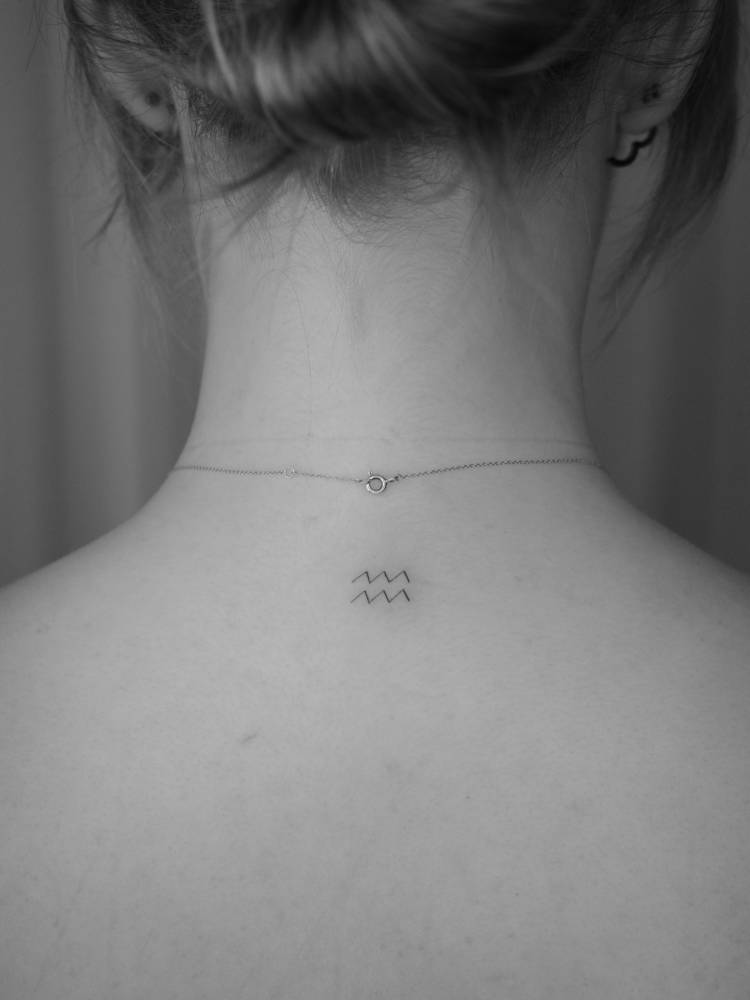 Minimalistic style Aquarius zodiac symbol tattooed on the upper back.