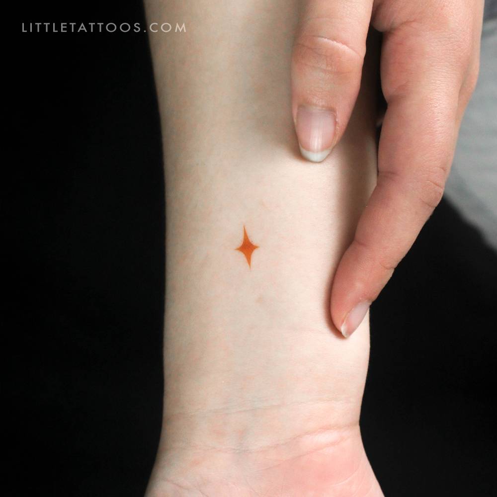 Tiny minimalistic yellow star temporary tattoo located on the wrist.