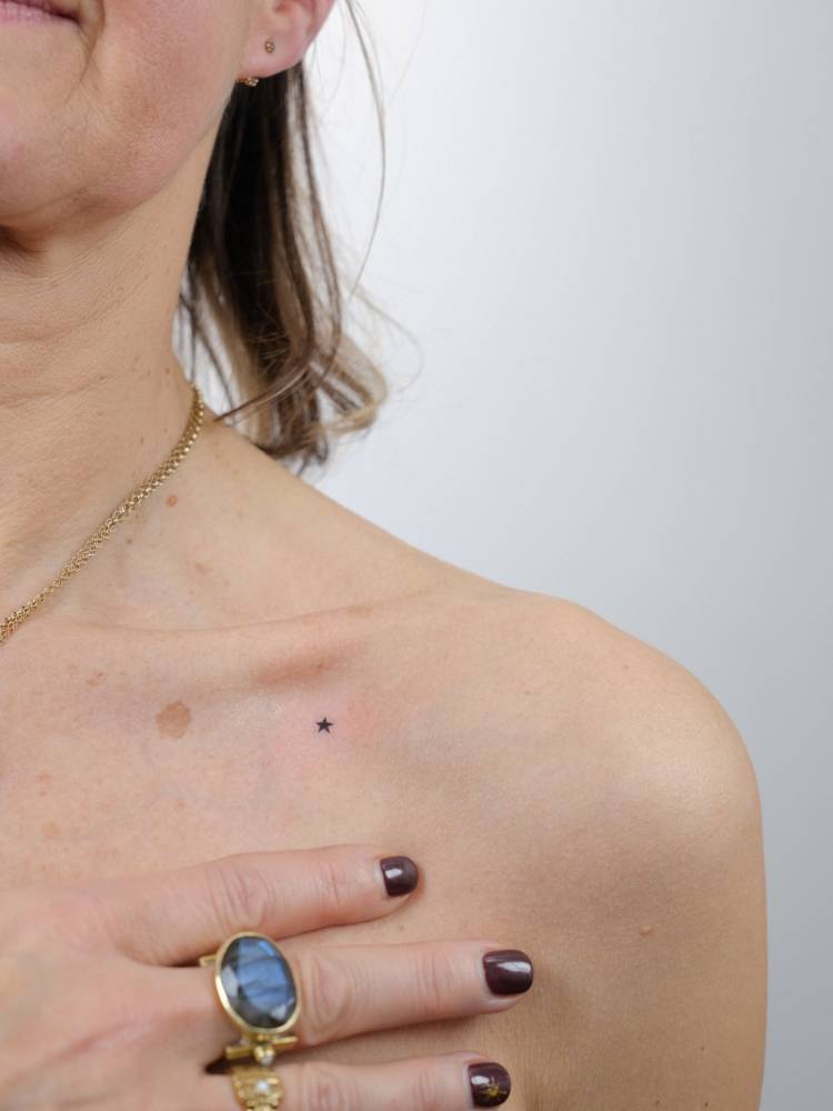 Micro star tattoo located on the collarbone, done in minimalistic style.
