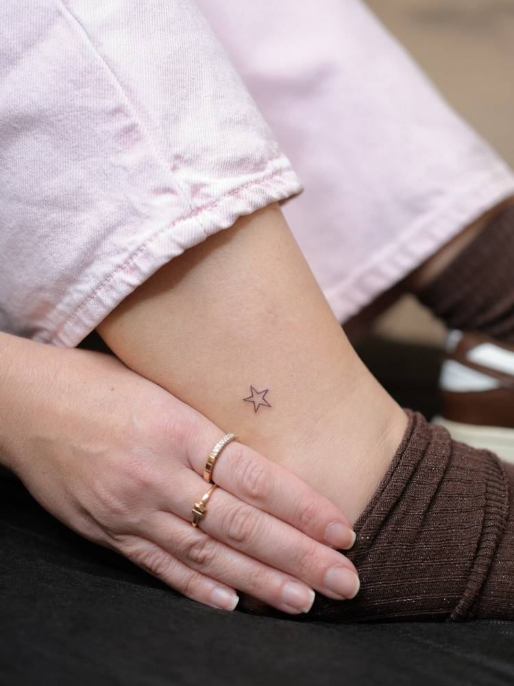 Minimalistic star tattoo in fine line style placed on the ankle.