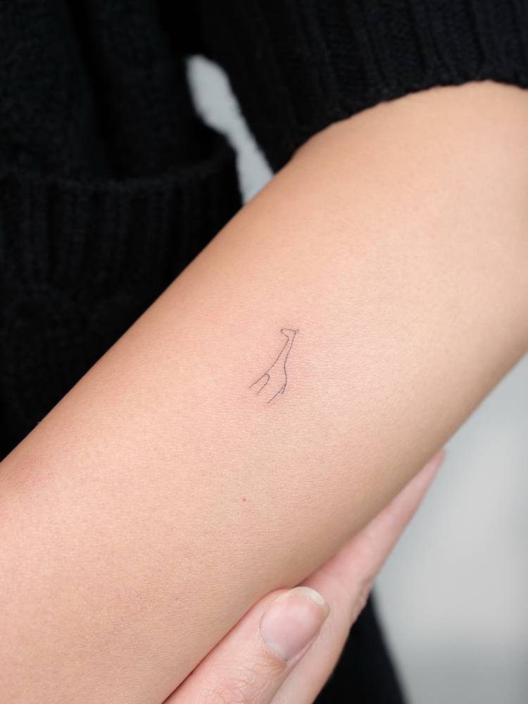Minimalistic one line giraffe tattoo located on the forearm.