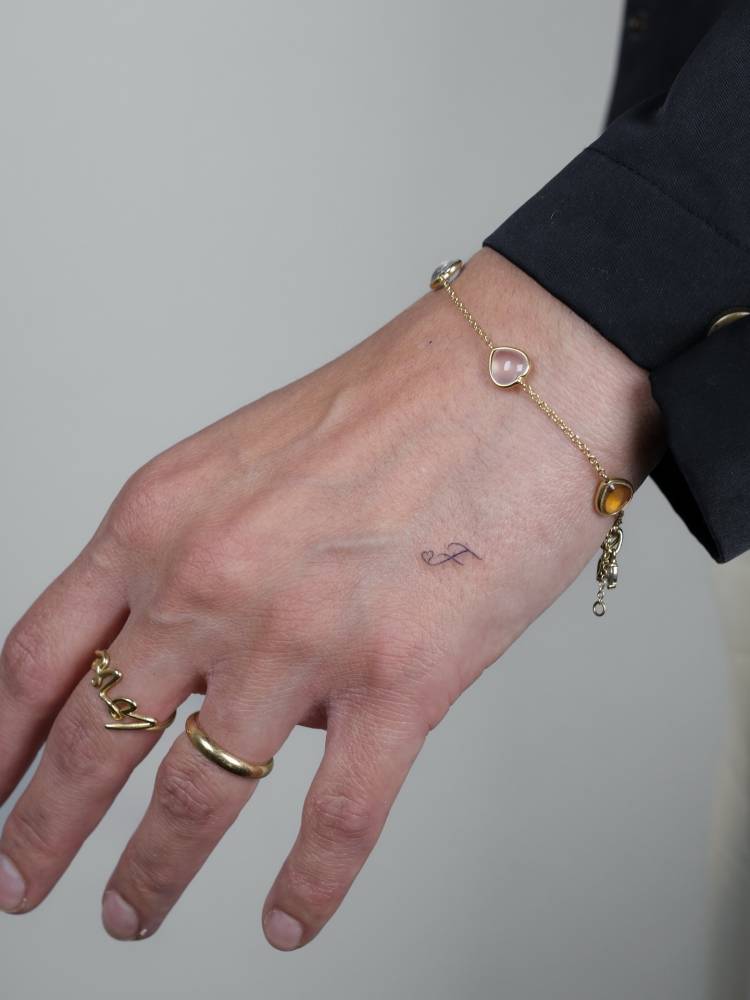 Little letter "F" tattoo in handwritten font.