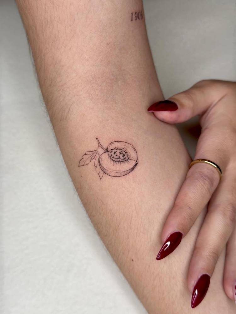 Illustrative style peach tattoo located on the inner forearm.