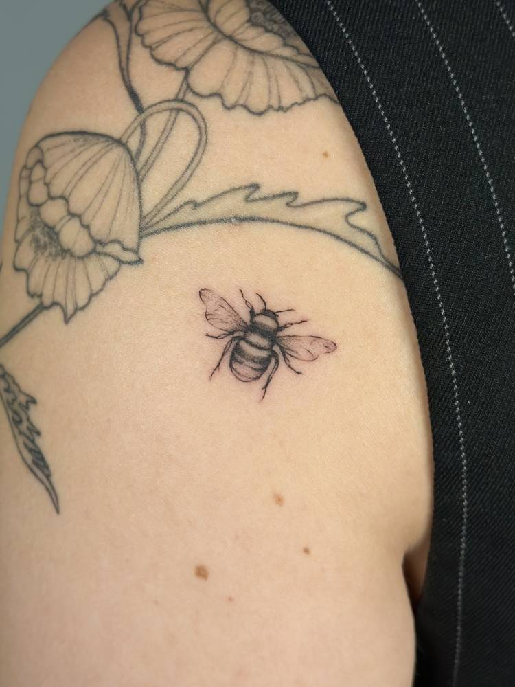 Bee tattoo in illustrative style located on the shoulder.