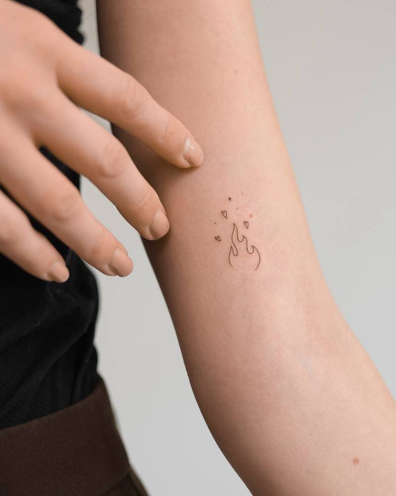 Fire tattoo in fine line style located on the inner arm.