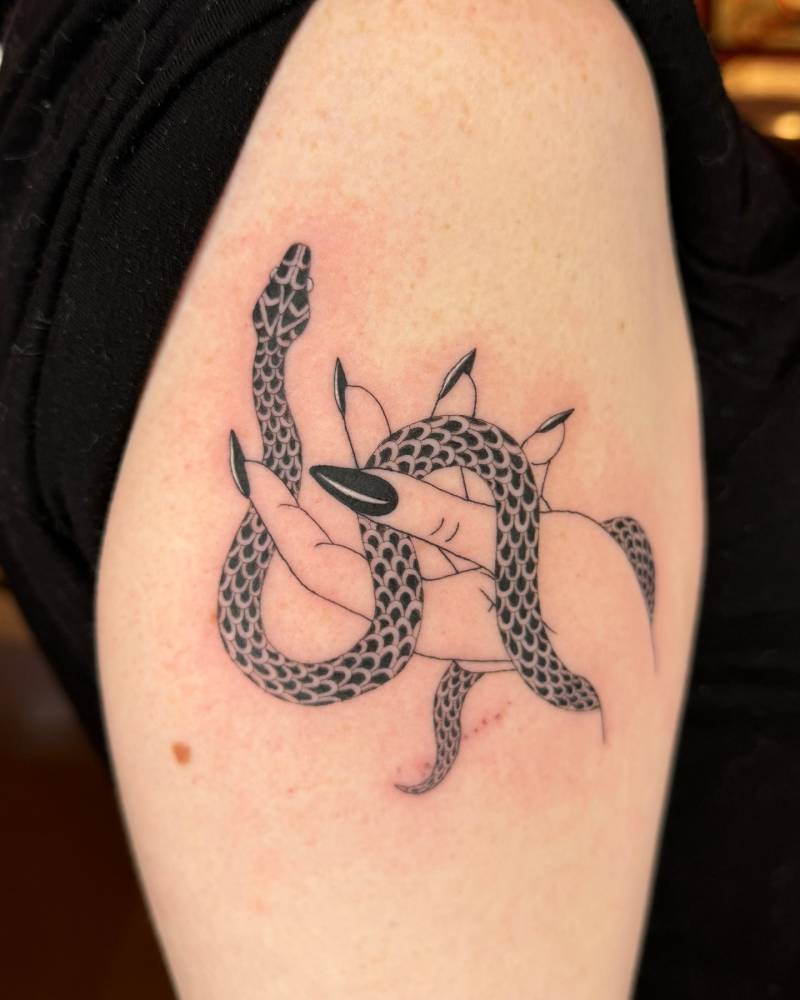 Hand holding a snake tattooed on the upper arm, done in illustrative style.