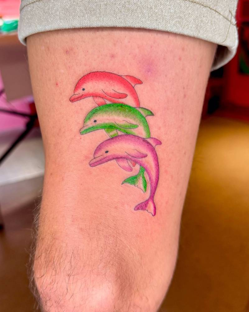 Three dolphins tattoo in illustrative style located on the thigh.