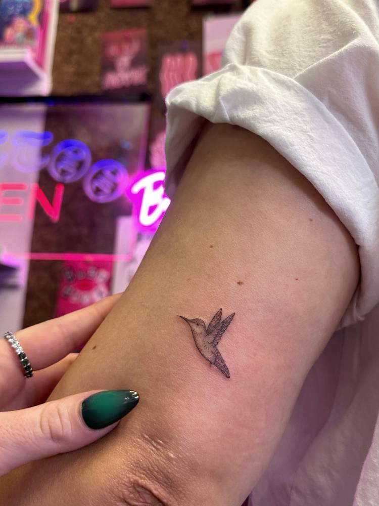 Little hummingbird tattoo in illustrative style located on the tricep.