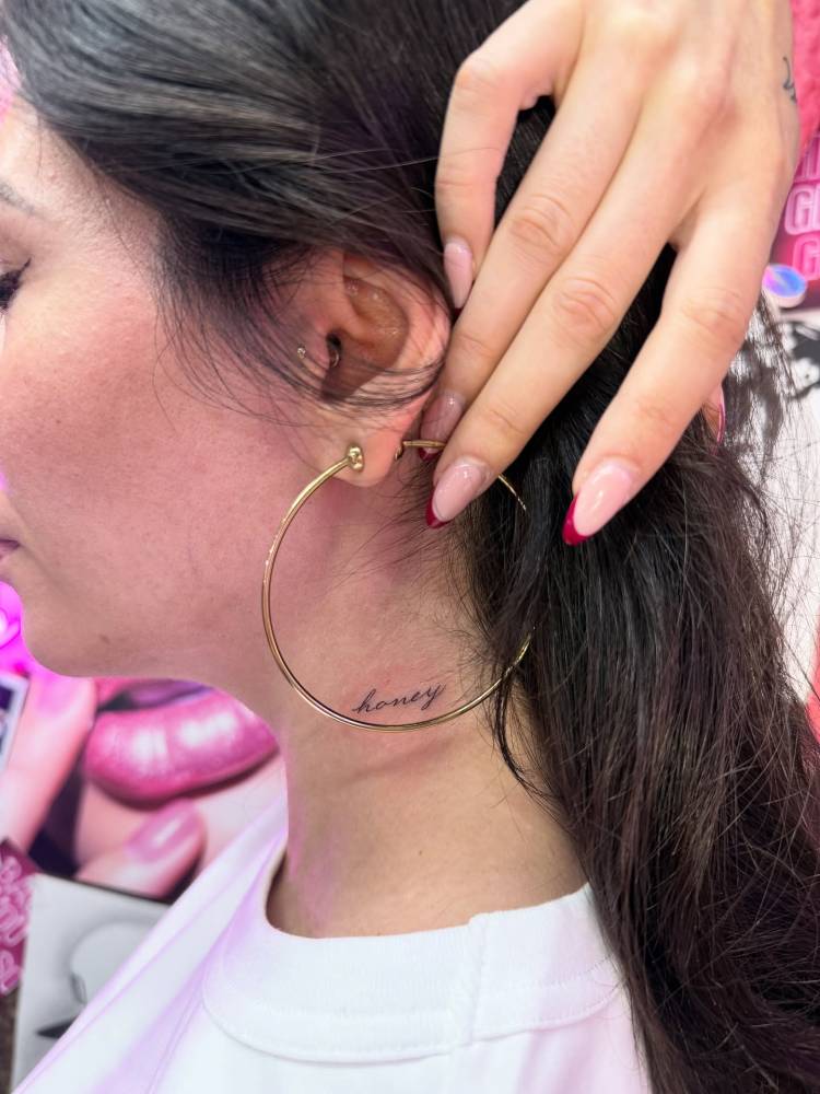 Lettering tattoo of the word "honey" placed on the neck.