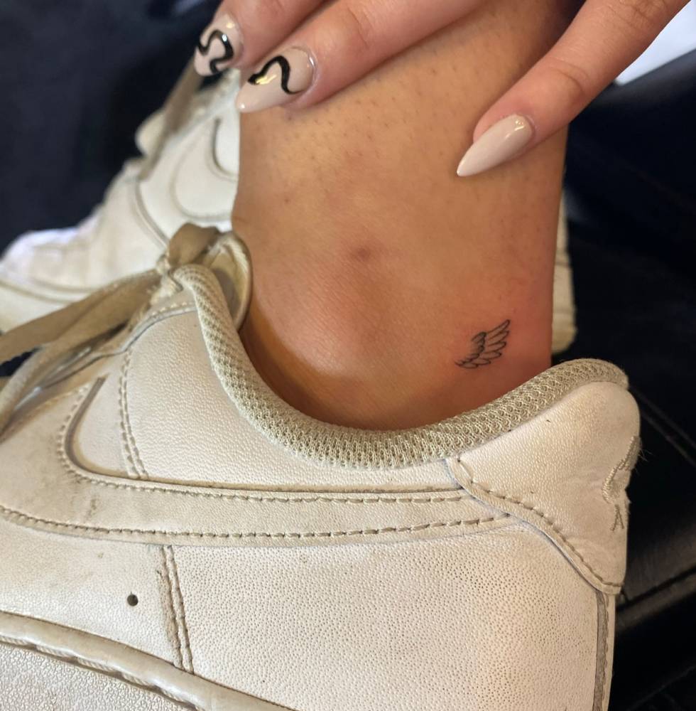 Tiny wing in illustrative style located on the ankle.