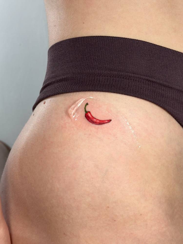 Illustrative style red chili tattoo located on the hip.